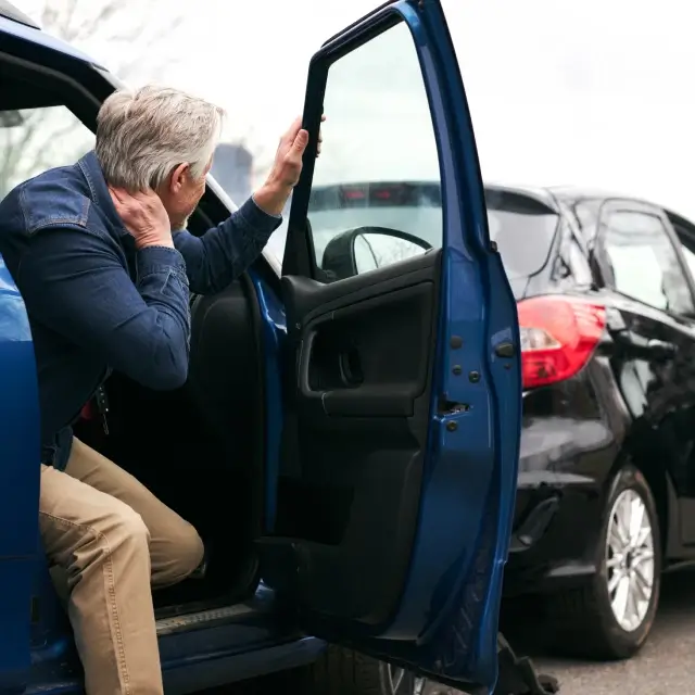 a man sitting in a car with his hand on the door