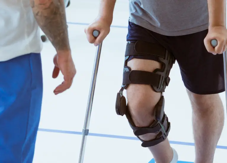 a person walking with crutches and knee braces