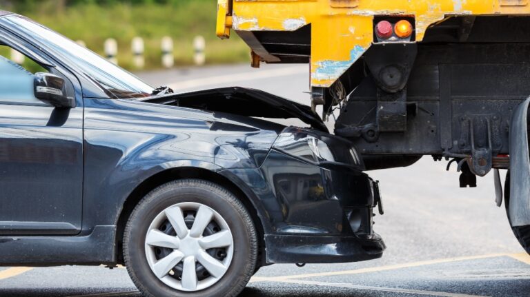 accident on the road involving black car and yellow truck