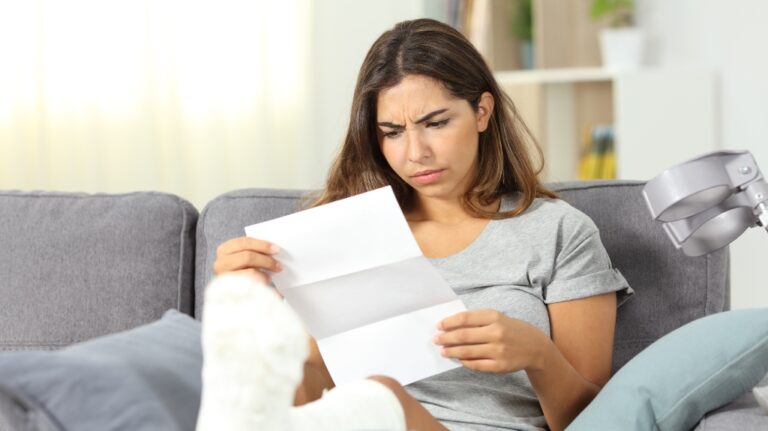 Worried disabled woman reading a letter sitting on a couch