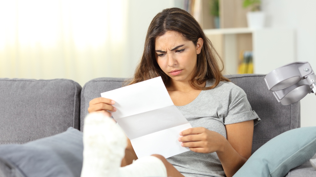 Worried disabled woman reading a letter sitting on a couch