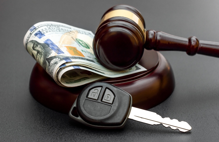 Judge's gavel with car key and money on black