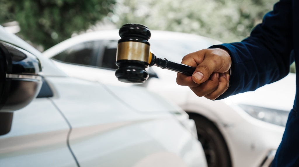 lawyer holding judge's gavel standing in front of car