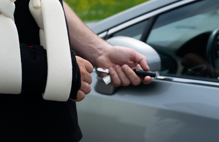 man with a plaster cast on his arm holds car keys in his hands