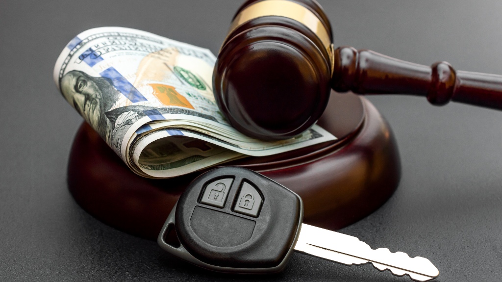 Judge's gavel with car key and money on black.