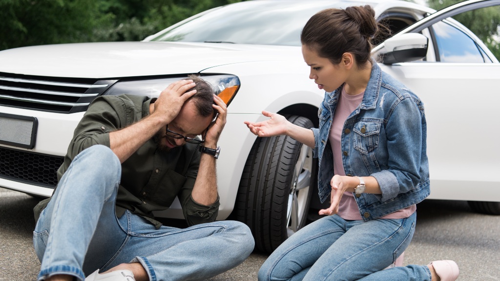 driver sitting near man on road after car accident