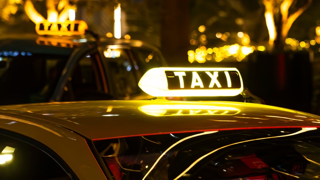 yellow taxi cab with a lit-up TAXI sign on the roof