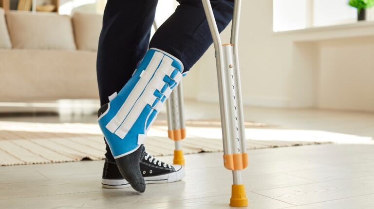 leg of man walking with crutches in ankle brace with support adjustable strap fracture fixator