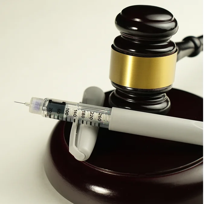 a syringe and gavel on a wooden block