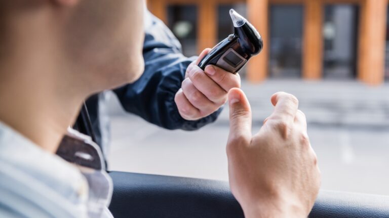 policeman giving breathalyzer to driver in car