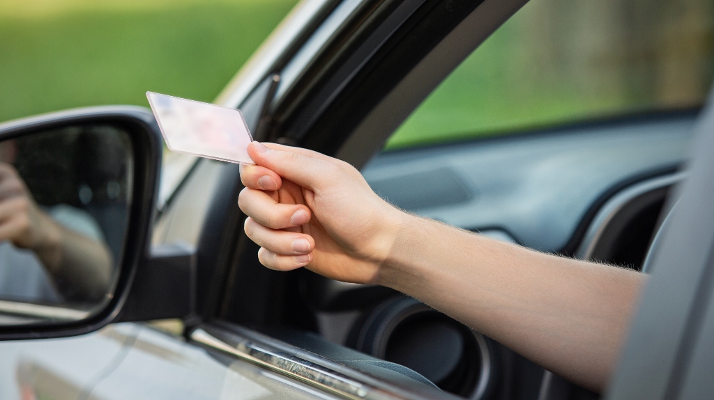 person hand out of the car window holding the driver license