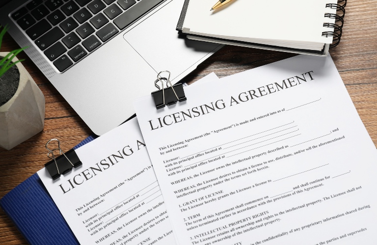 Licensing agreement documents, stationery and laptop on wooden desk