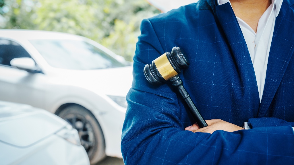 lawyer is holding judge's gavel and standing in front of a car
