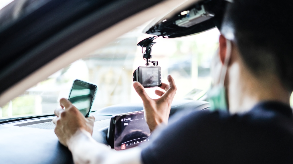 Close up Technician Hand with Car Camera and Smartphone Inside Car and Blur Man as a Foreground