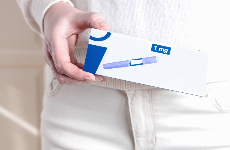 Woman in white cloths holding a pack of Ozempic injection pen for diabetics and weight loss